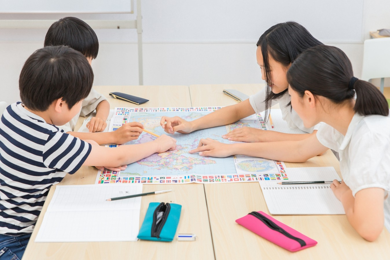 世界地図を囲み、仲間と一緒に学ぶ子どもたち